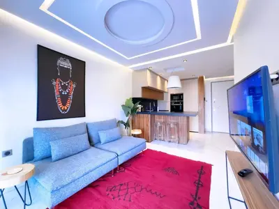 a living room with a blue couch and a red rug at Appt de Luxe avec Terrasse,PiscinePartagée & wifi in Marrakech
