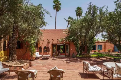 a courtyard with chairs and trees and a building at Villa Grenade in Marrakech