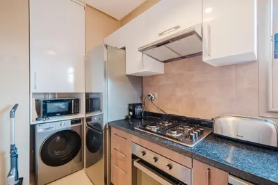 a kitchen with a stove and a washer and dryer at 3 Bedroom Apartment with Pool View Prestigia in Marrakech