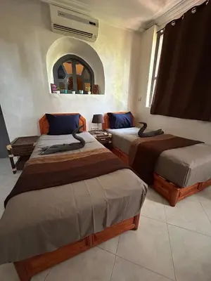 two beds sitting in a room with a mirror at Maison à la Palmeraie avec piscine et parking à Marrakech in Marrakech