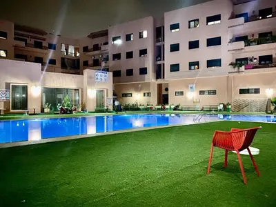 a red chair in front of a swimming pool in a building at Magnifique F3 au Riad Arfoud avec piscine in Marrakech