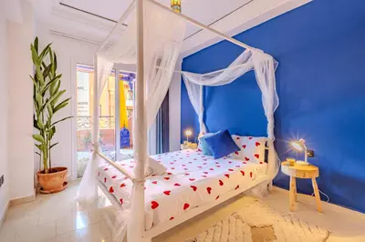 a bedroom with a white canopy bed with a blue wall at Boho chic retreat in Marrakech