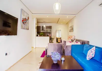 a living room with a blue couch and a table at Appartement Chic et Lumineux, Proche Gare in Marrakech
