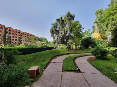 a walkway in a park with a building in the background at Apartment with pool and garden in Marrakech