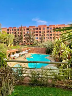 a resort with a pool in front of a building at Apartment with pool and garden in Marrakech