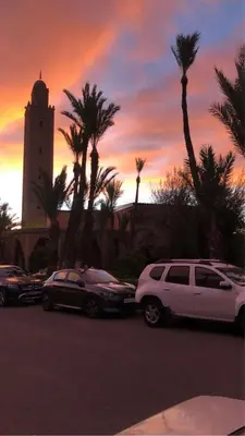 a group of cars parked in a parking lot with a sunset at Riad& 4 Chambres Avec La piscine in Marrakech