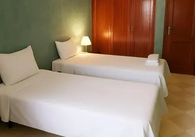two beds in a hotel room with white sheets at Appart AMITAF in Marrakech