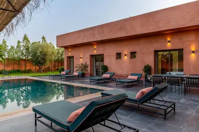 a house with a swimming pool and chairs next to a building at Villa Izia - Quiet, nature and private pool in Marrakech
