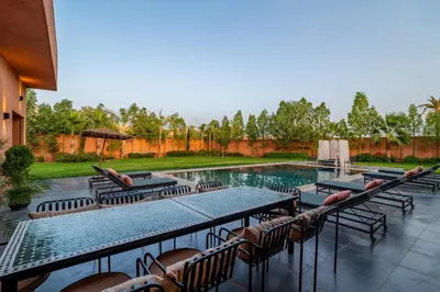 a patio with tables and chairs next to a swimming pool at Villa Izia - Quiet, nature and private pool in Marrakech