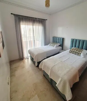 a bedroom with two beds and a window at Comfortable poolside apartment near city center in Marrakech