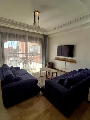 a living room with two blue couches and a tv at Comfortable poolside apartment near city center in Marrakech