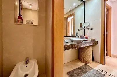 a bathroom with a sink and a toilet and a mirror at Sunny apartment with rooftop Water Park included in Dar Caïd Layadi
