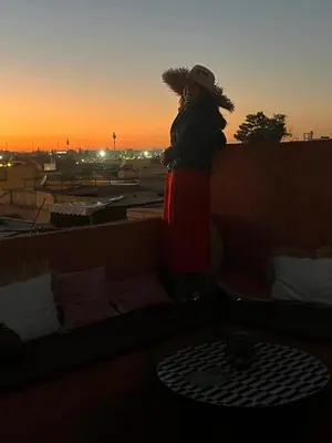 a woman standing on a rooftop watching the sunset at Riad L'EncensOriental & Spa in Marrakech