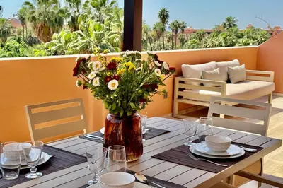 a table with a vase of flowers on a balcony at Penthouse with Rooftop and Jardin Majorelle View in Marrakech