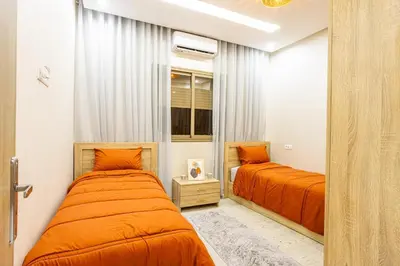 two beds in a bedroom with orange sheets at HAGS Apartment - Traditional Modern Apartment, full AC, 10m from airport in Marrakech
