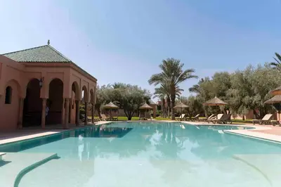 a swimming pool at a resort with umbrellas at Résidence AYDA Riad Villa Hanane in Marrakech