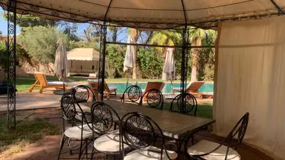 a table and chairs under a pavilion with a pool at Villa Palmeraire Marrakech, Private pool, Private Hamam in Marrakech