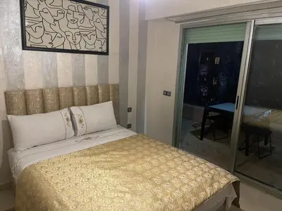 a bedroom with a bed and a sliding glass door at LA PERLE ANDALOUSE Quartier HIVERNAGE in Marrakech