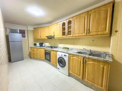 a kitchen with wooden cabinets and a washer and dryer at Elegant 2-BR, Pool And Parking Hivernage Centre in Marrakech
