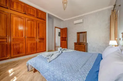 a bedroom with a blue bed and wooden cabinets at L'essentiel au soleil piscine parking in Marrakech