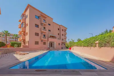 an apartment with a swimming pool in front of a building at L'essentiel au soleil piscine parking in Marrakech