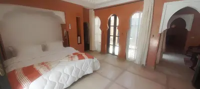 a bedroom with a bed with orange walls and windows at Villa Marrakchia - Palais d'hôtes in Marrakech