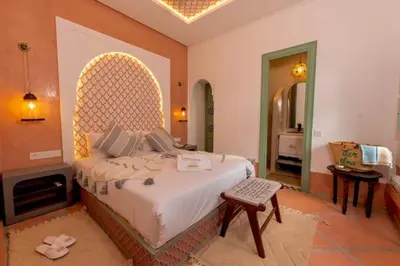 a bedroom with a large bed and a room with a fireplace at Riad DAR ELMA NOI in Marrakech