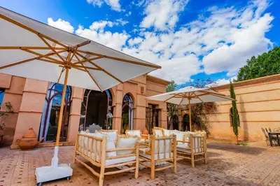 a group of chairs and umbrellas in front of a building at Villa des SONGES in Marrakech