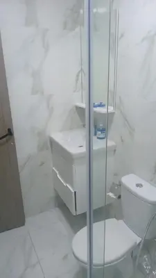 a white bathroom with a toilet and a glass shower at Logement Confort Résidence Fermée avec Piscine in Marrakech