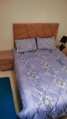 a bed with a purple comforter and pillows at Logement Confort Résidence Fermée avec Piscine in Marrakech
