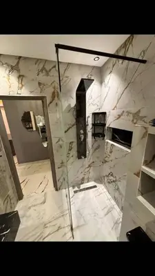 a marble bathroom with a glass shower and a mirror at Appartement moderne in Marrakech