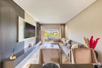 a living room with a couch and a tv at Spacious luxury 3BR by the pool in Marrakech