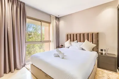 a bedroom with a large white bed with a window at Spacious luxury 3BR by the pool in Marrakech