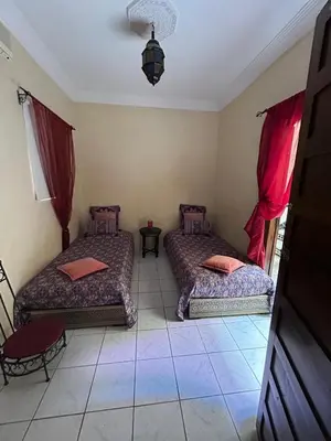 two beds in a room with red curtains at Riad Marrakech in Marrakech