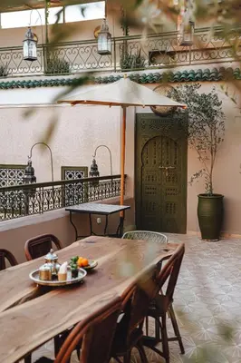 a wooden table with a plate of food and an umbrella at Nahla Wellness in Marrakech