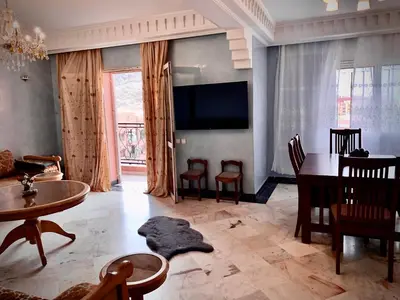 a living room with a table and chairs and a television at Appartement Marrakechi in Marrakech