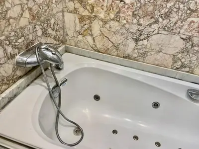 a white bath tub with a shower in a bathroom at Appartement Marrakechi in Marrakech