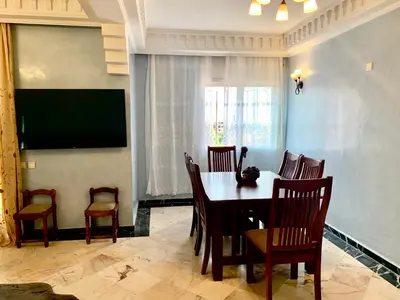 a dining room with a table and chairs and a television at Appartement Marrakechi in Marrakech