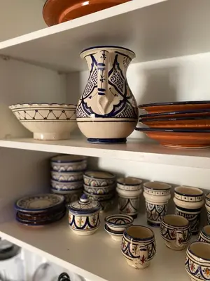 a shelf full of vases and bowls in a cabinet at Berber Atlas Marrakech with Pool in Marrakech