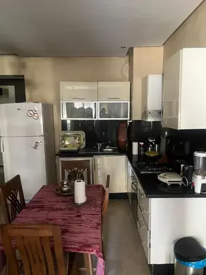 a kitchen with a table and a white refrigerator at nice apartment and good location in Marrakech