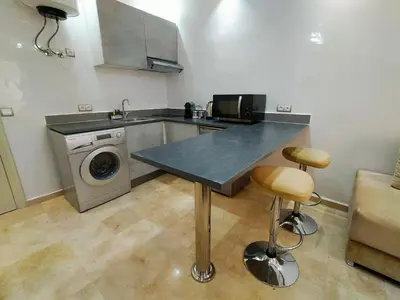 a kitchen with a table and a washing machine at Cozy Apt in Heart of Marrakech, Walk Everywhere in Marrakech
