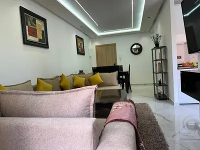 a living room with a couch and yellow pillows at Aube Hivernage appartement in Marrakech