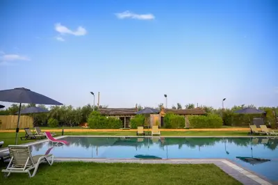 a pool with chairs and umbrellas in a yard at Oléa villa & lodge in Marrakech