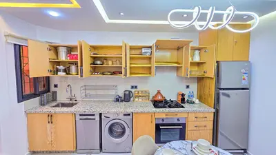 a kitchen with wooden cabinets and a washer and dryer at Appartement Chic et Confortable, Netflix, PS4 & Wi-Fi Centre Marrakech in Marrakech