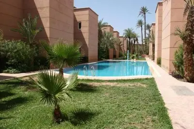 a swimming pool in front of a building with palm trees at 3 bedroom duplex with swimming pool in Marrakech