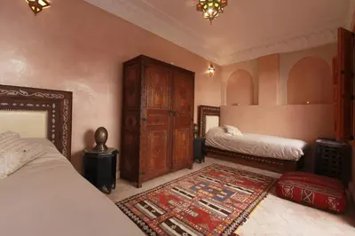 a bedroom with two beds and a rug at Riad Khalid Zrika Marrakech in Marrakech