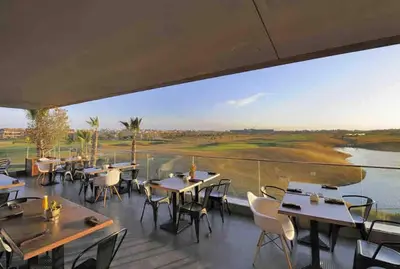 a restaurant with tables and chairs and a large window at Cozy RC golf view pool & Atlas fiber optic 2 bedrooms in Marrakech