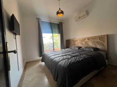 a bedroom with a bed and a tv and a window at L'oasis d'Atlas Golf Resort in Marrakech