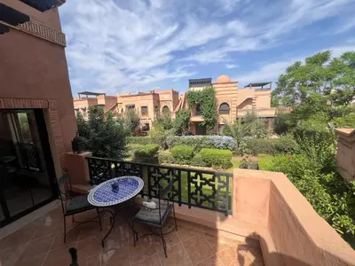 a patio with a table and chairs on a balcony at L'oasis d'Atlas Golf Resort in Marrakech