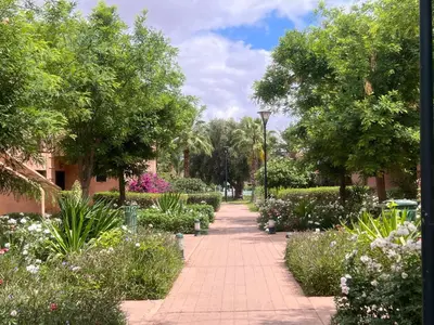 a walkway through a garden with flowers and trees at L'oasis d'Atlas Golf Resort in Marrakech